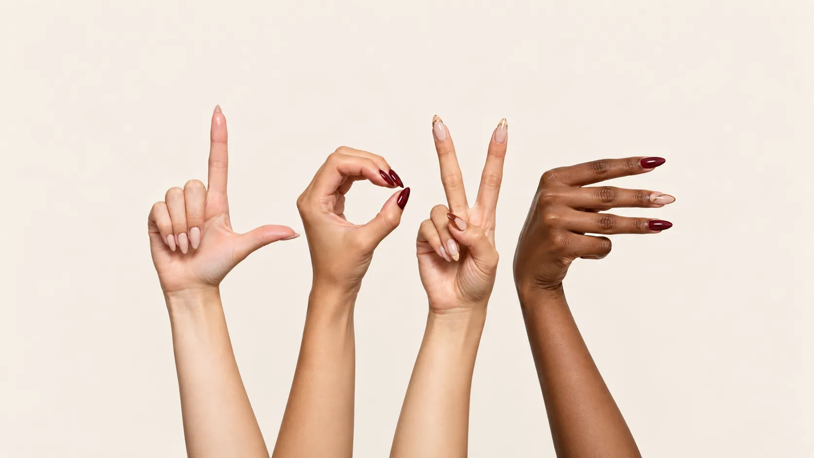 Four hands with almond nails spelling the word love